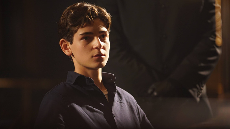 Bruce Wayne (David Mazouz) speaks calmly with a gloved man behind him Gotham