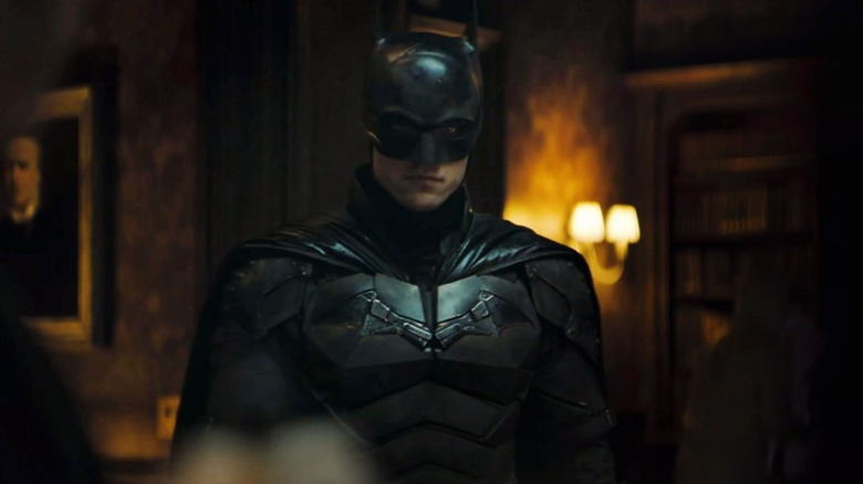 Robert Pattinson as Batman, standing in a lavish apartment, in The Batman