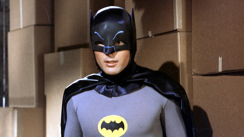 Adam West as Batman, standing in front of cardboard boxes, in the 1966 Batman series