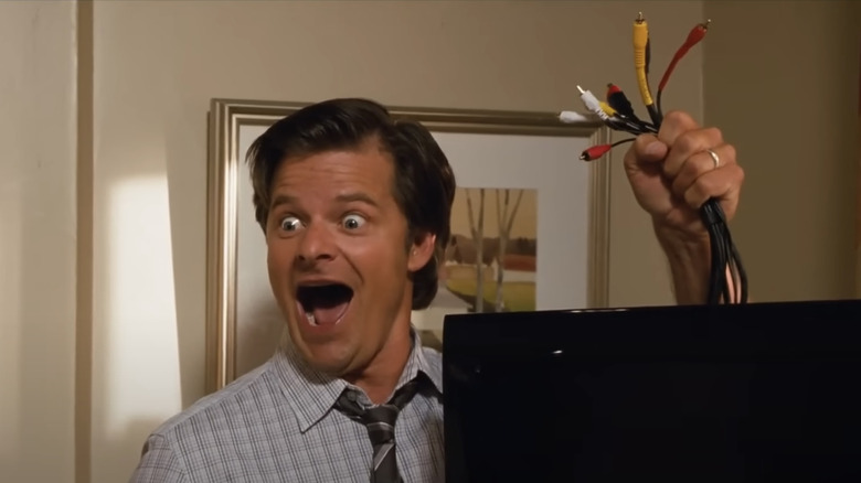 Steve Zahn as Frank Heffley, excited and holding a bundle of cords behind a television set
