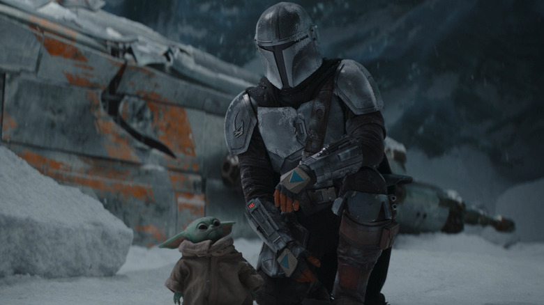 Din Djarin kneeling by Grogu in an ice cave in The Mandalorian season 2