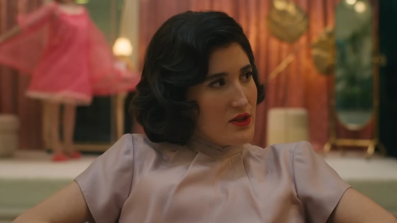Peg talking while sitting in an armchair