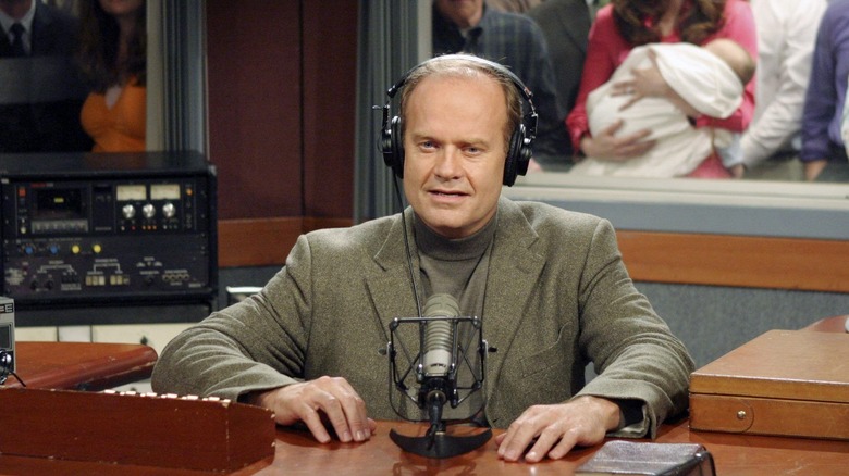 Frasier speaks into mic in front of main cast