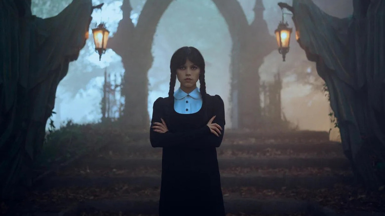 Wednesday stands outside a foreboding gate in Wednesday
