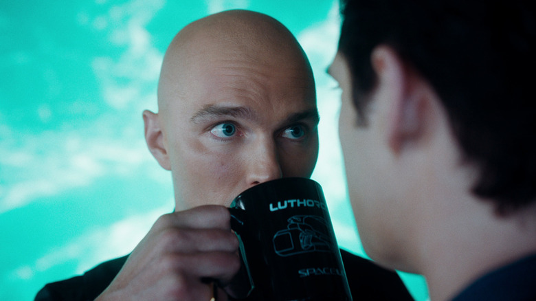 Lex Luthor (Nicholas Hoult) drinks coffee out of a LuthorCorp mug in front of Clark Kent/Superman (David Corenswet) in Superman (2025).