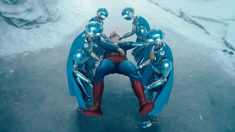 Four robots carrying a weakened Clark Kent/Superman (David Corenswet) in the Fortress of Solitude in Superman (2025).