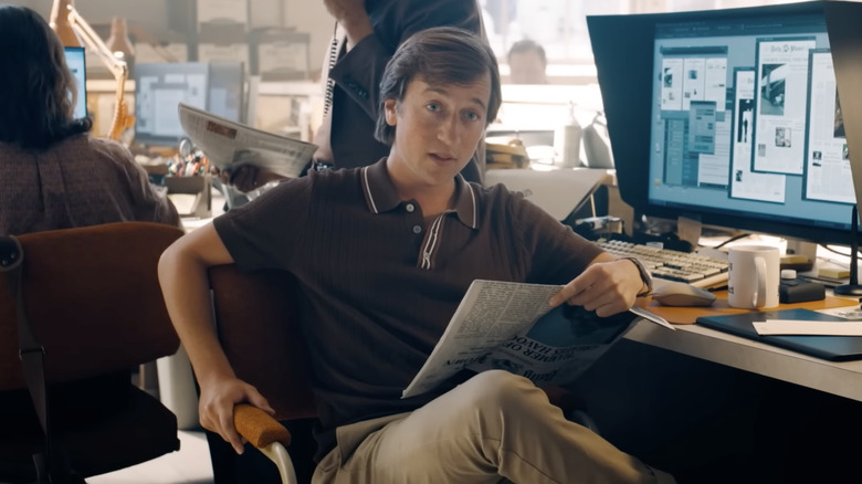 Jimmy Olsen (Skyler Gisondo) reads a newspaper at his desk in the Daily Planet offices in Superman (2025).