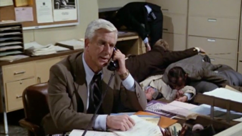 Frank Drebin taking a phone call in front of dead bodies in Police Squad