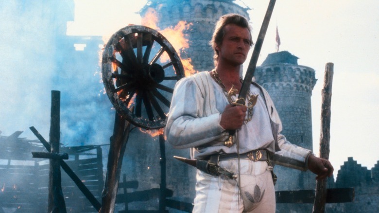 Rutger Hauer stands in front of sword flaming wheel in Flesh and Blood