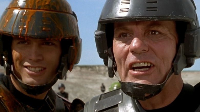 Casper van Dien and Michael Ironside wearing dirty helmets in Starship Troopers