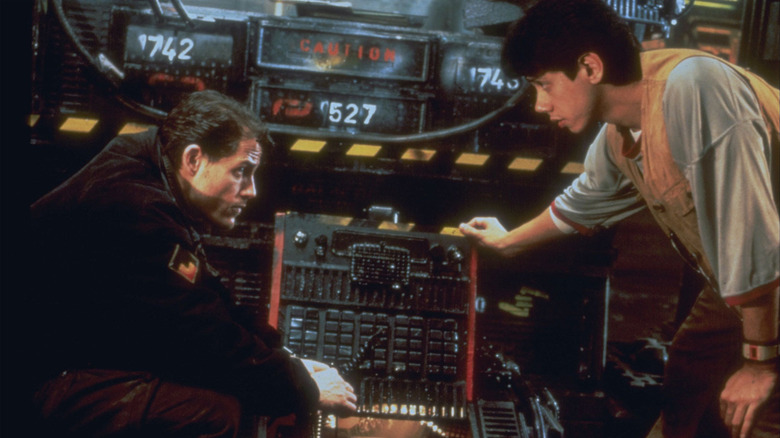 Two men converse over futuristic equipment
