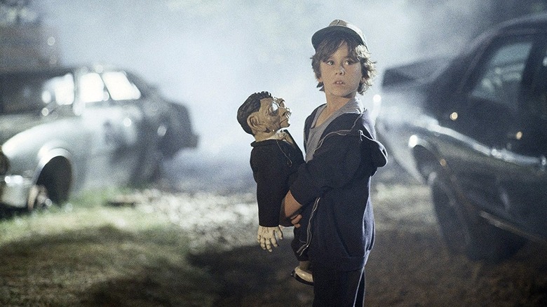 A young boy holds a horrifying ventriloquist's dummy