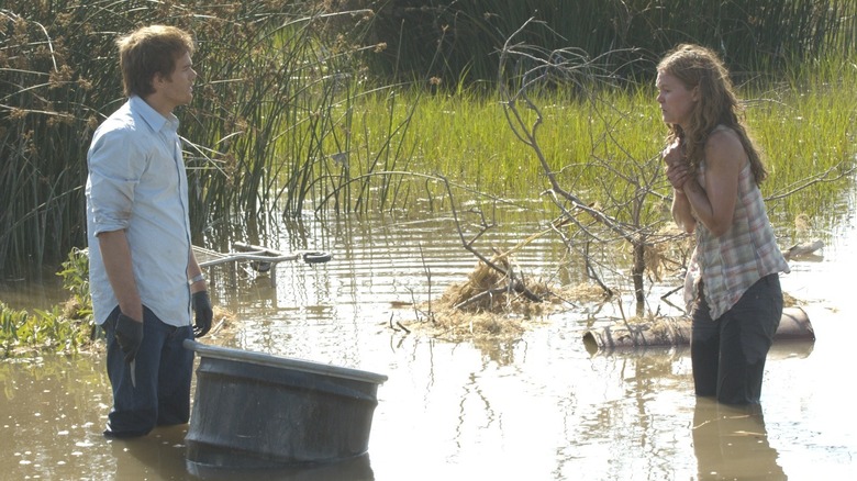 Michael C. Hall and Julia Stiles as Dexter and Lumen, standing next to a barrel in a swamp on Dexter