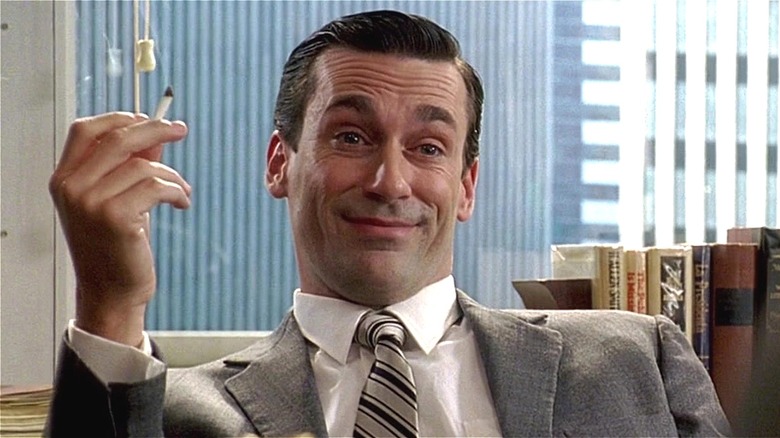 Jon Hamm holding a cigarette and smiling
