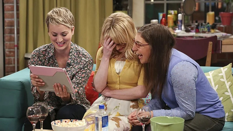 Penny Bernadette and Amy laughing at a tablet on The Big Bang Theory