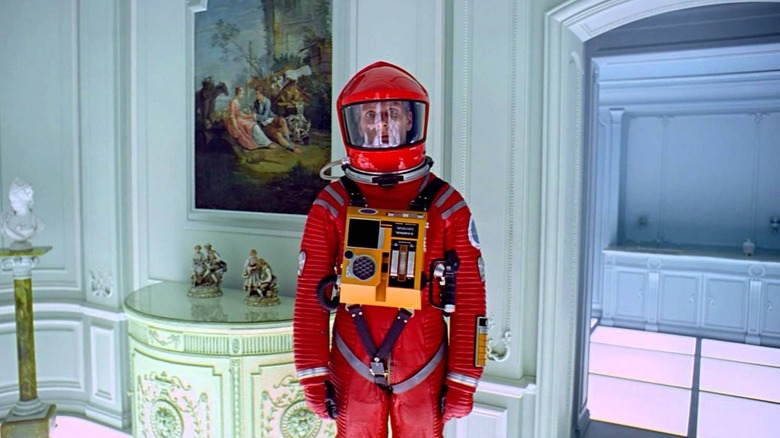 David Bowman (Keir Dullea) stands in his red astronaut suit in a bright white neoclassical room in 2001: A Space Odyssey