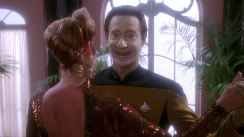 Data, smiling in a fake fashion, dancing in a ballroom with a pretty woman in Star Trek: The Next Generation.