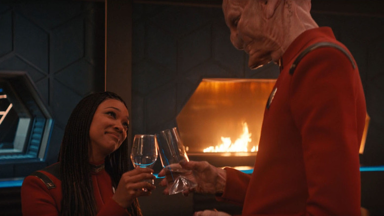 Michael Burnham and Saru, toasting by a fireplace in Star Trek: Discovery