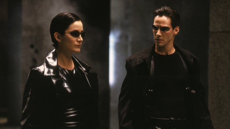 Trinity and Neo standing in full gear and sunglasses, ready to fight in The Matrix