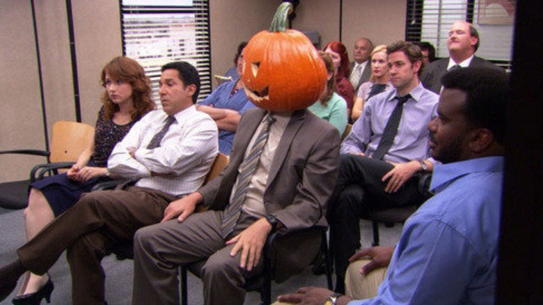 Dwight sits in a meeting with a pumpkin head