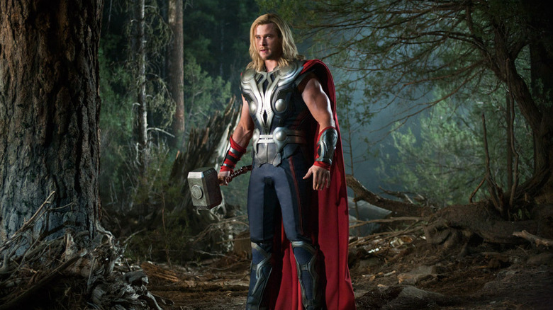 Thor (Chris Hemsworth) stands in the woods with Mjolnir in Avengers