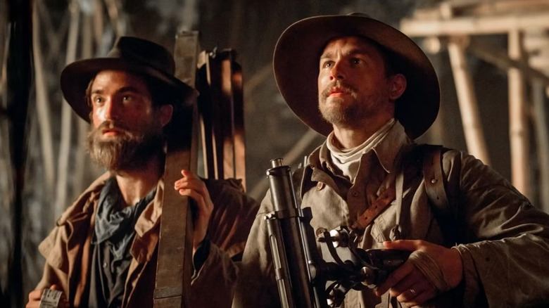 Corporal Henry Costin standing next to Percy Fawcett, both wearing exploratory equipment, in The Lost City of Z