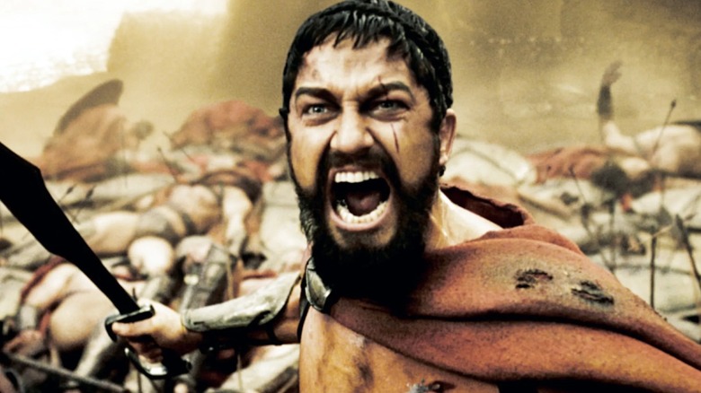 Gerard Butler as King Leonidas with his sword drawn behind piles of bodies in 300