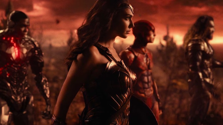 Cyborg, Wonder Woman, The Flash and Aquaman stood facing right against a red landscape in Justice League
