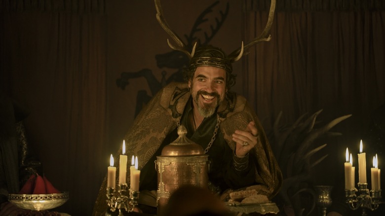 Daniel Ings as Lyonel Baratheon rocking an antler crown and sitting at a table in A Knight of the Seven Kingdoms