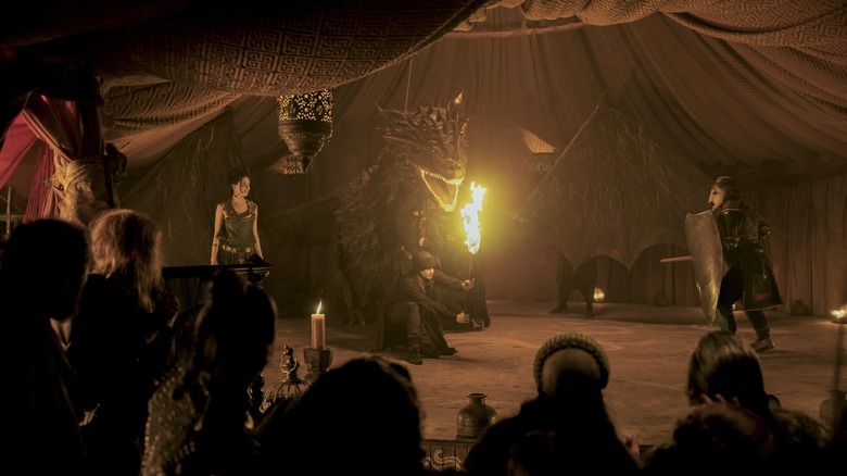 Tanzyn Crawford as Tanselle putting on an elaborate puppet show with a mockup of a fire-breathing dragon in A Knight of the Seven Kingdoms