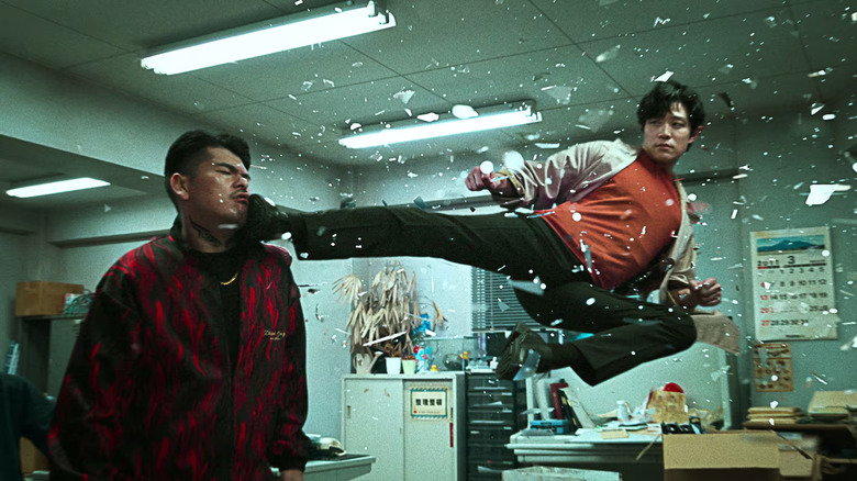 Ryohei Suzuki as Ryo Saeba, surrounded by shards of glass, kicking an opponent in the face in City Hunter