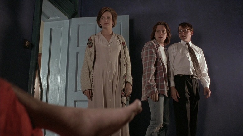 Juliet, David, and Alex looking at a dead body in Shallow Grave