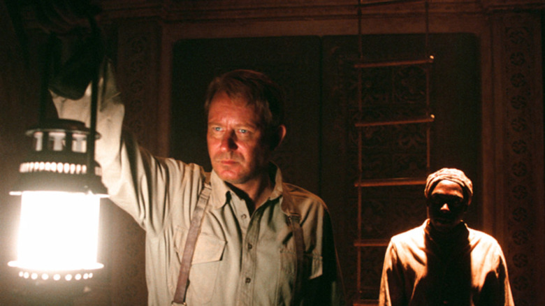Father Merrin with a lantern in Exorcist The Beginning