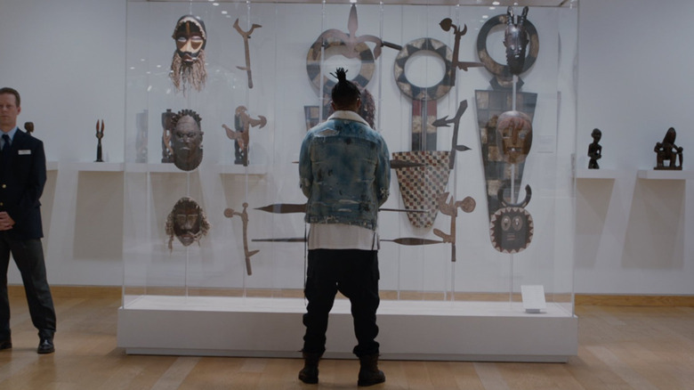 Erik Killmonger (Michael B Jordan) stands in front of a case of artifacts in Black Panther