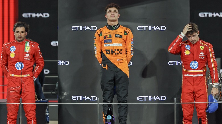 Carlos Sainz, Charles Leclerc, and Lando Norris standing together on an F1 podium