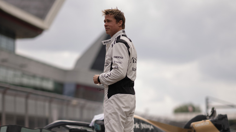 Brad Pitt as racer Sonny Hayes standing on a track near his car in F1: The Movie