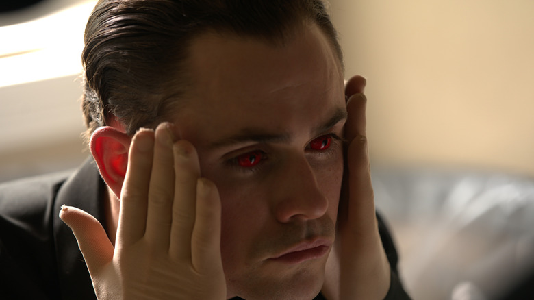 Arthur, wearing red contacts, checks his face in Faces of Death