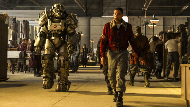 Maximus walking next to a soldier in Power Armor at a Brotherhood of Steel camp in Fallout