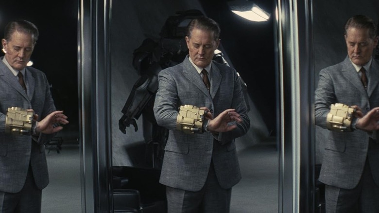 Kyle MacLachlan as Hank MacLean examining an arm band in a mirror in Fallout