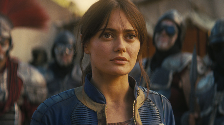 Ella Purnell as Lucy MacLean standing in front of a legion of armed soldiers looking concerned in Fallout