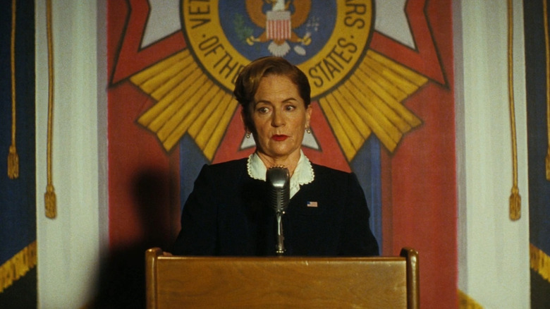 Martha Kelly as Representative Diane Welch standing behind a podium and delivering a speech in Fallout season 2