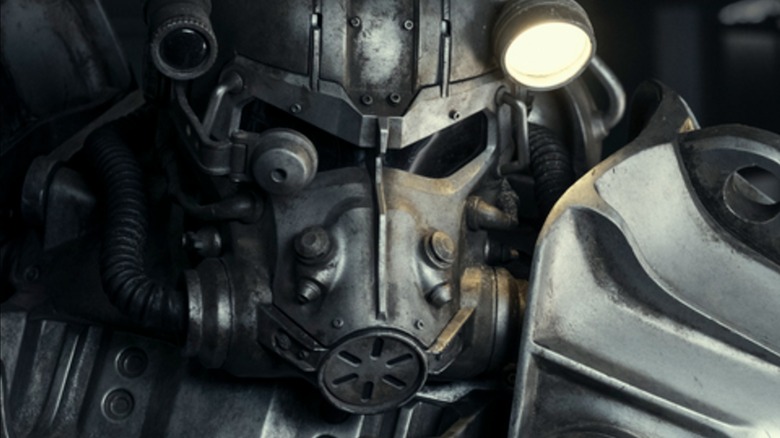 A person wearing a power armor suit using their helmet flashlight on Fallout