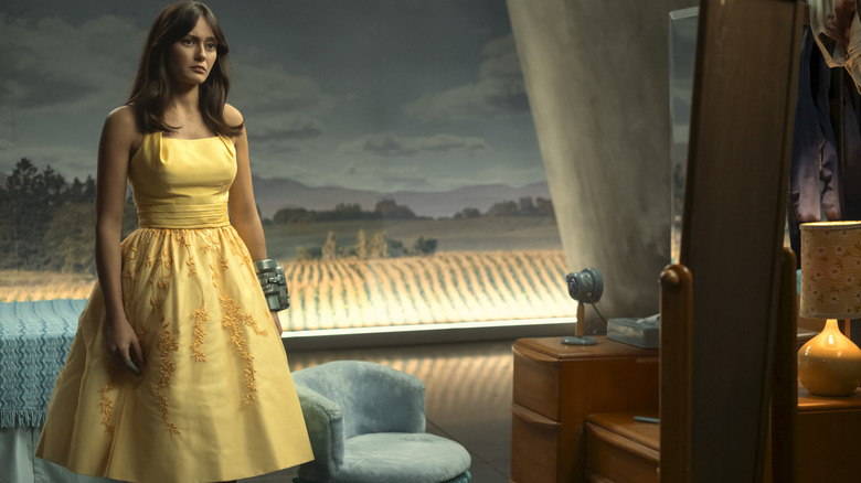 Ella Purnell as Lucy MacLean wearing a yellow dress in a room with old-fashioned tech décor in Fallout