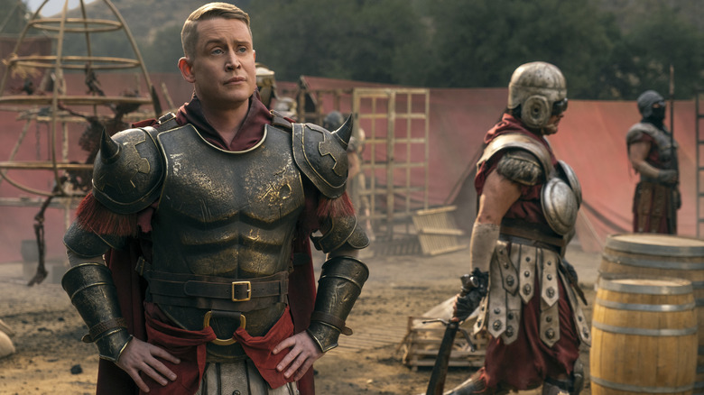 Macaulay Culkin as Lacerta Legate dressed in Roman armor and standing outside in a dusty encampment in Fallout