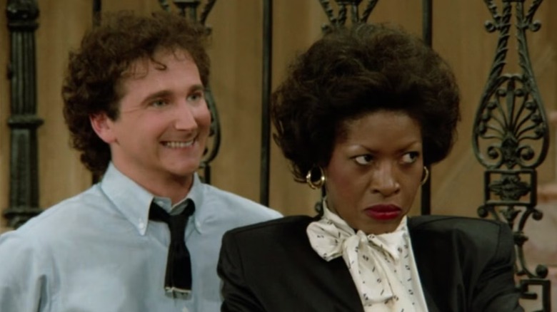 Larry Appleton (Mark Linn-Baker) and Harriette Winslow (Jo Marie Payton) stand next to each other, as Larry smiles and Harriette glares on an episode of Perfect Strangers