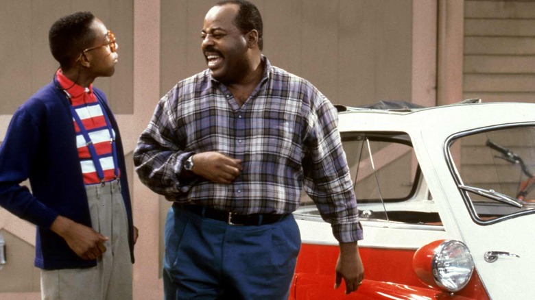 Carl Winslow looks angrily at Steve Urkel, in front of his car