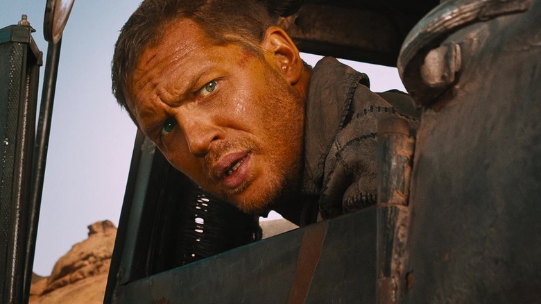 Tom Hardy as Max Rockatansky, poking his head out the window of a war rig in Mad Max: Fury Road
