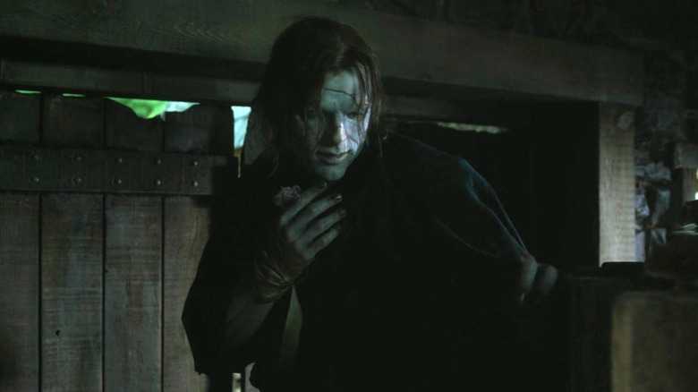 Frankenstein (2025) - Creature hiding in barn, holding mouse