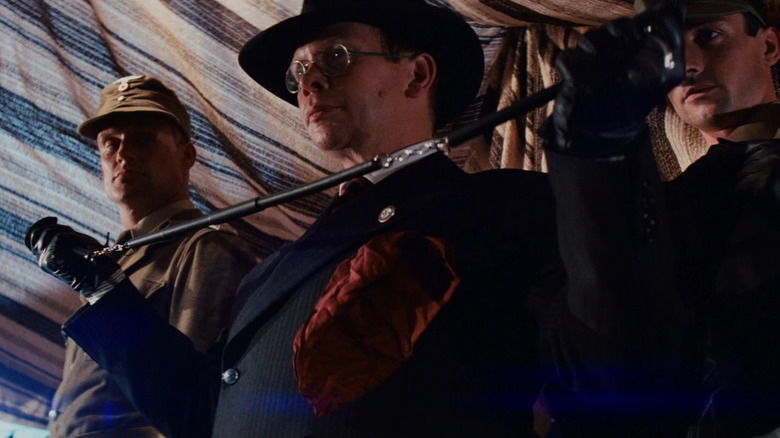 Toht holding his coat hanger in Raiders of the Lost Ark