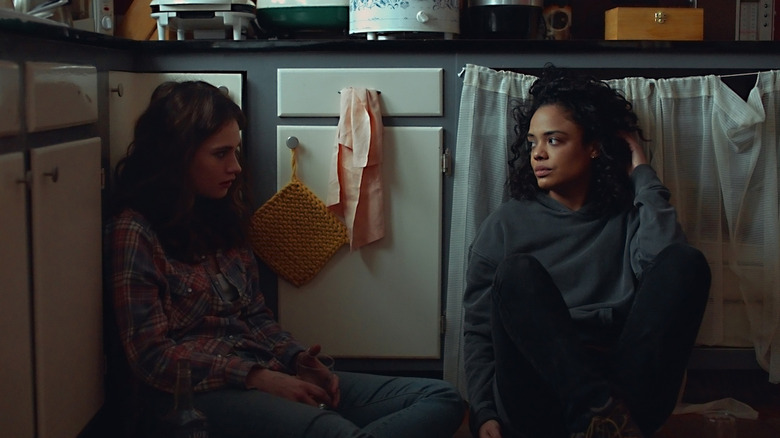 Two women sit on the kitchen floor with their backs against the cabinets. Both look dejected.